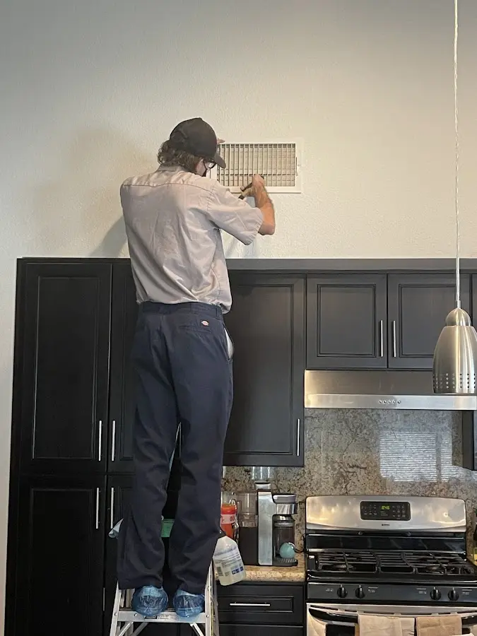 Technician inspecting an air vent during HVAC service in London